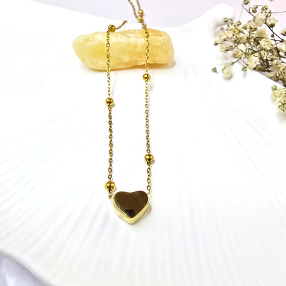 Close-up of Heart Bead Necklace on white shell background showing smooth finish.