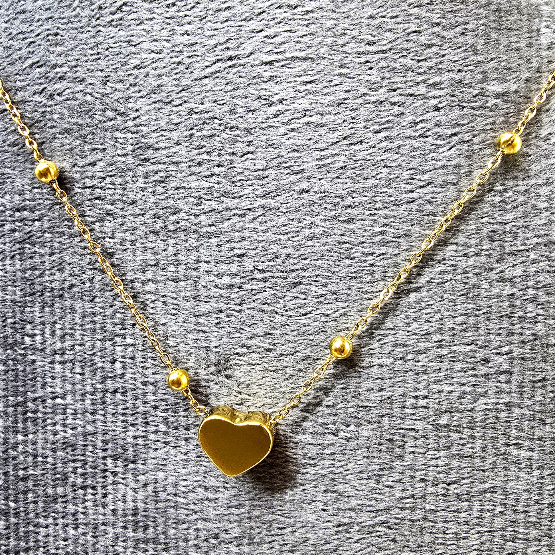 Heart Bead Necklace displayed on grey velvet background highlighting gold shine.