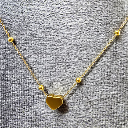 Heart Bead Necklace displayed on grey velvet background highlighting gold shine.