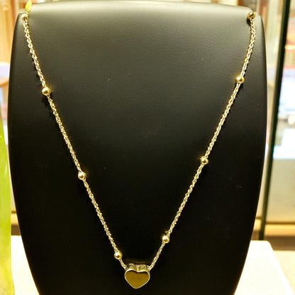 Necklace on black jewelry stand showing dainty design and polished heart pendant.