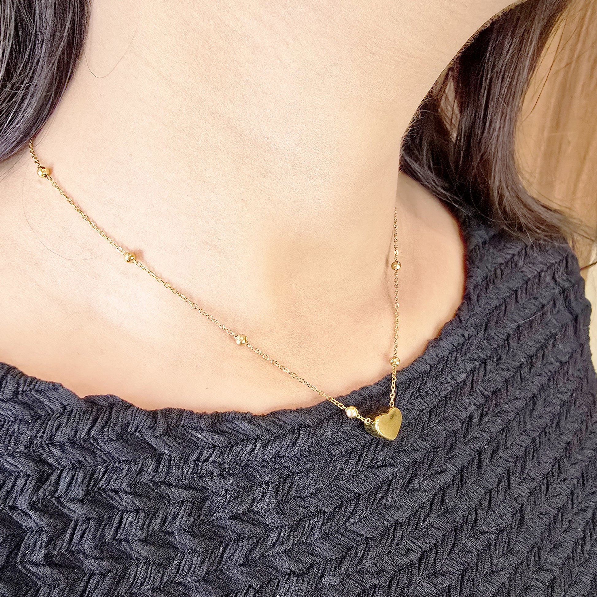 Model wearing Heart Bead Necklace – gold-toned chain with small heart pendant.