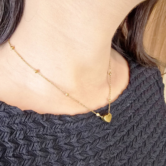 Model wearing Heart Bead Necklace – gold-toned chain with small heart pendant.