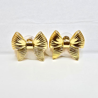 A pair of high-polish gold ribbed bow-shaped stud earrings displayed flat on a white background.