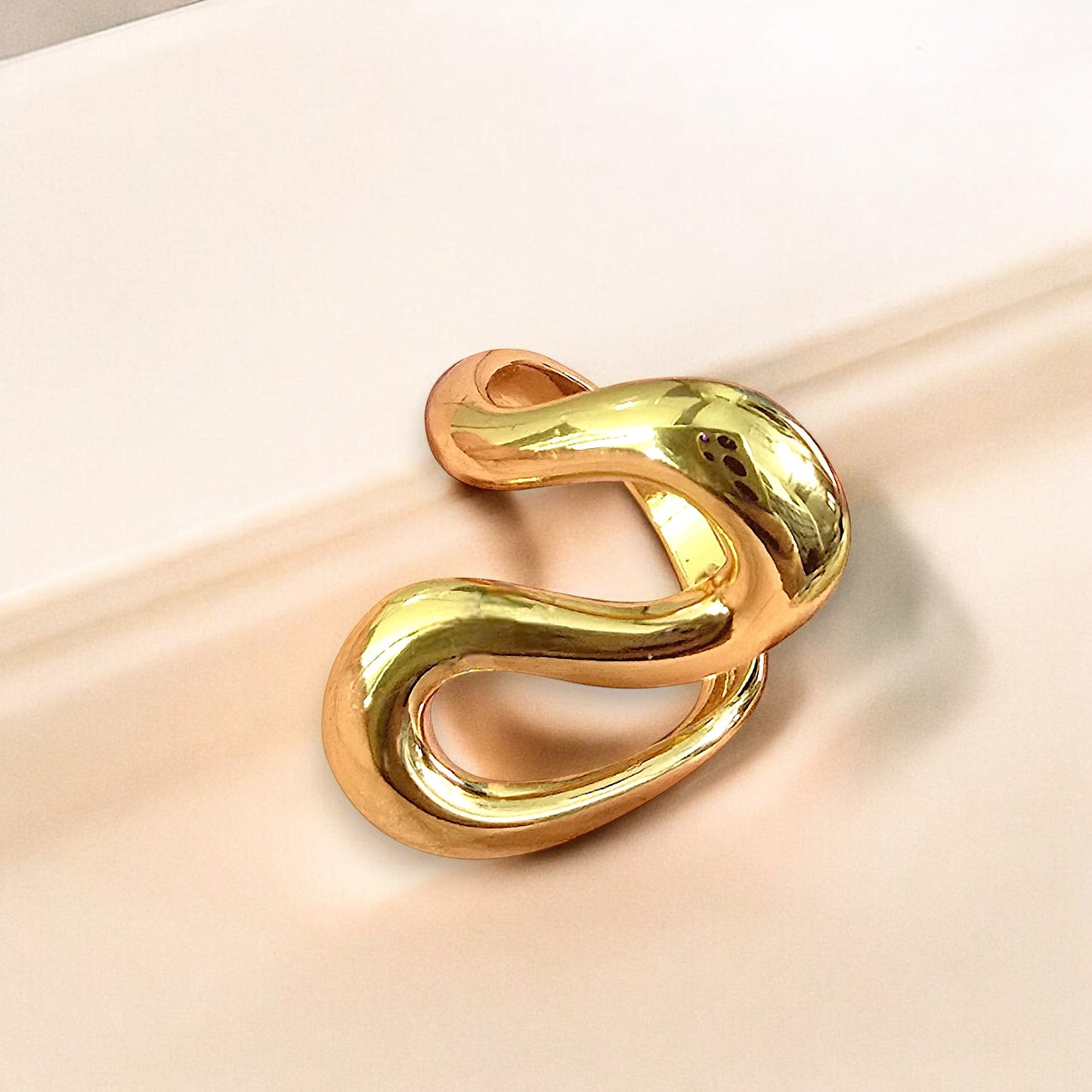 Zunari Charm Infinity Flow Ring with abstract wavy design in gold, displayed on soft beige background.