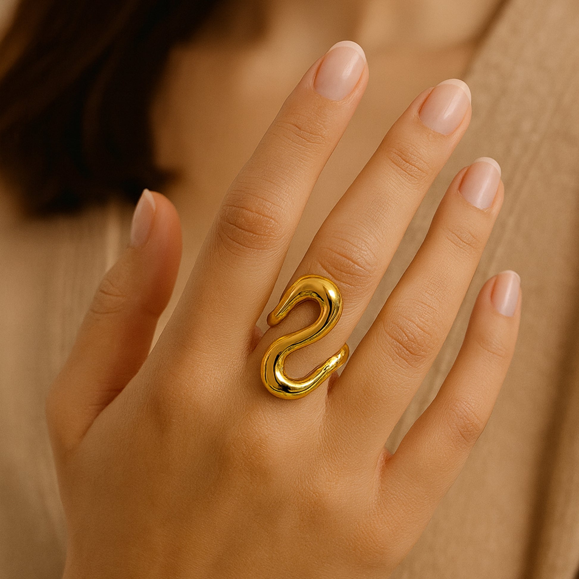 Zunari Charm gold Infinity Flow Ring on model’s hand, showcasing bold sculptural wave design in anti-tarnish finish.