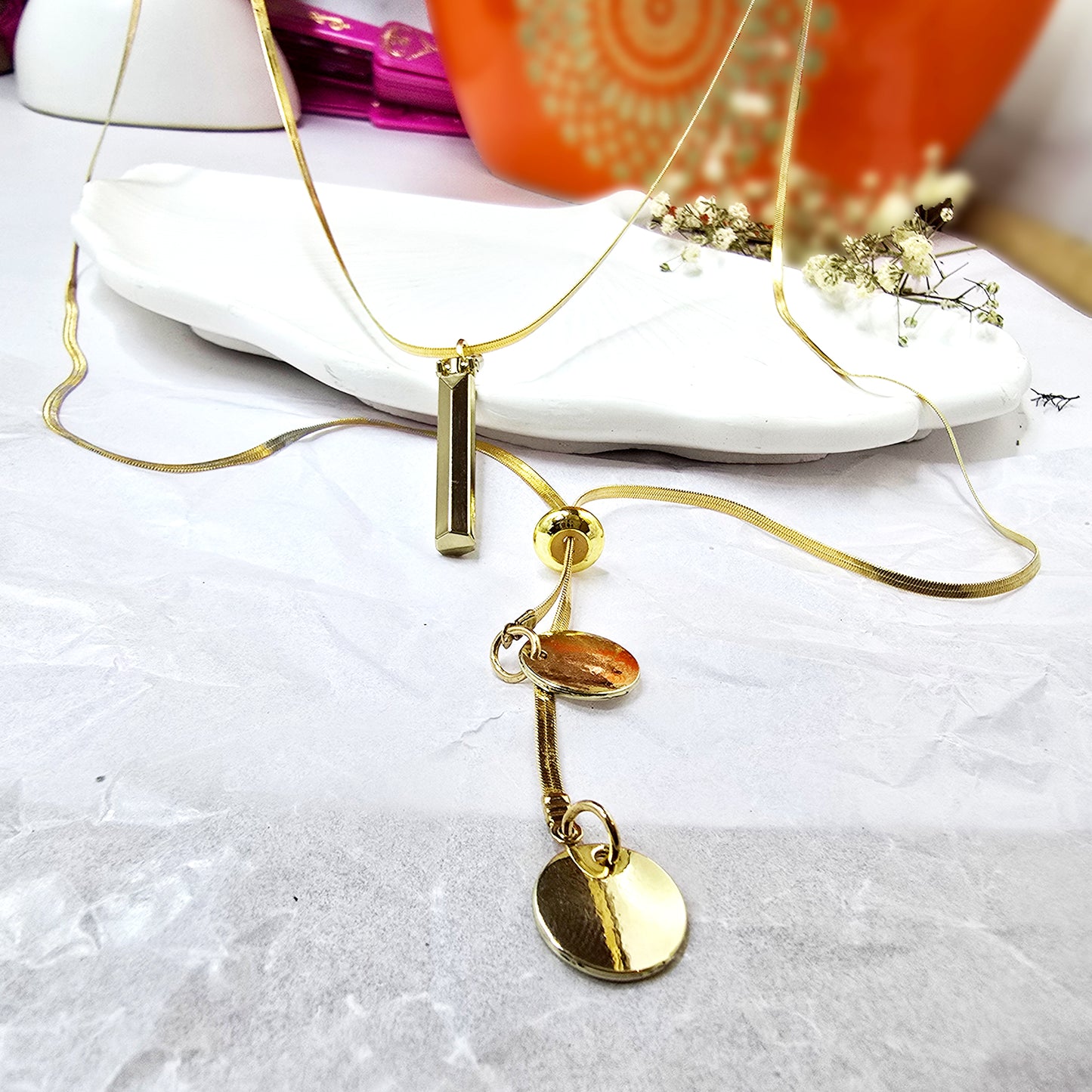 Close-up of gold Layered Charm Drop Necklace with bar and coin drops.