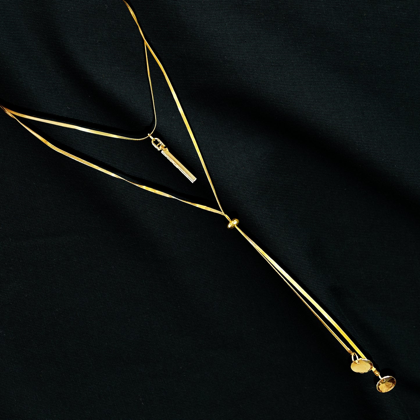 Layered Charm Drop Necklace flatlay on black fabric – chic and elegant