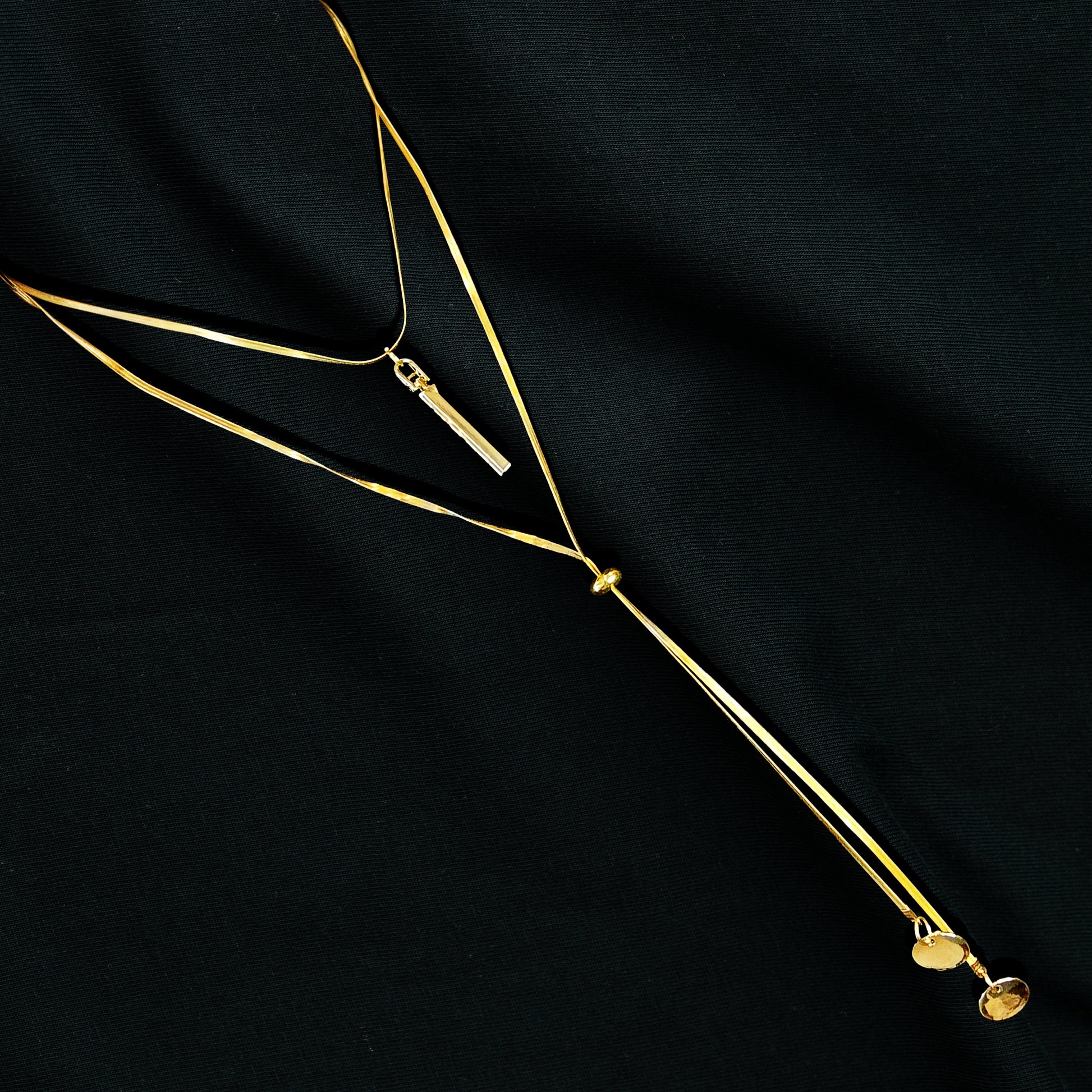 Layered Charm Drop Necklace flatlay on black fabric – chic and elegant