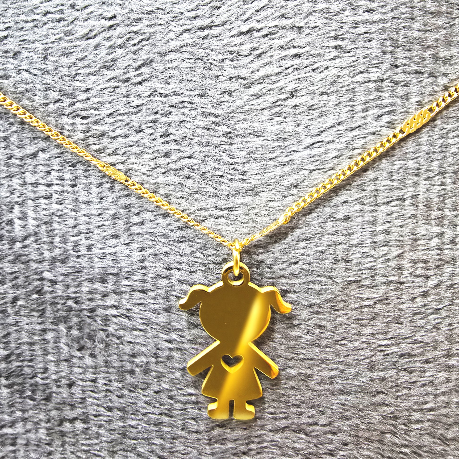 Gold little girl pendant necklace featuring a heart cutout on a grey textured display.