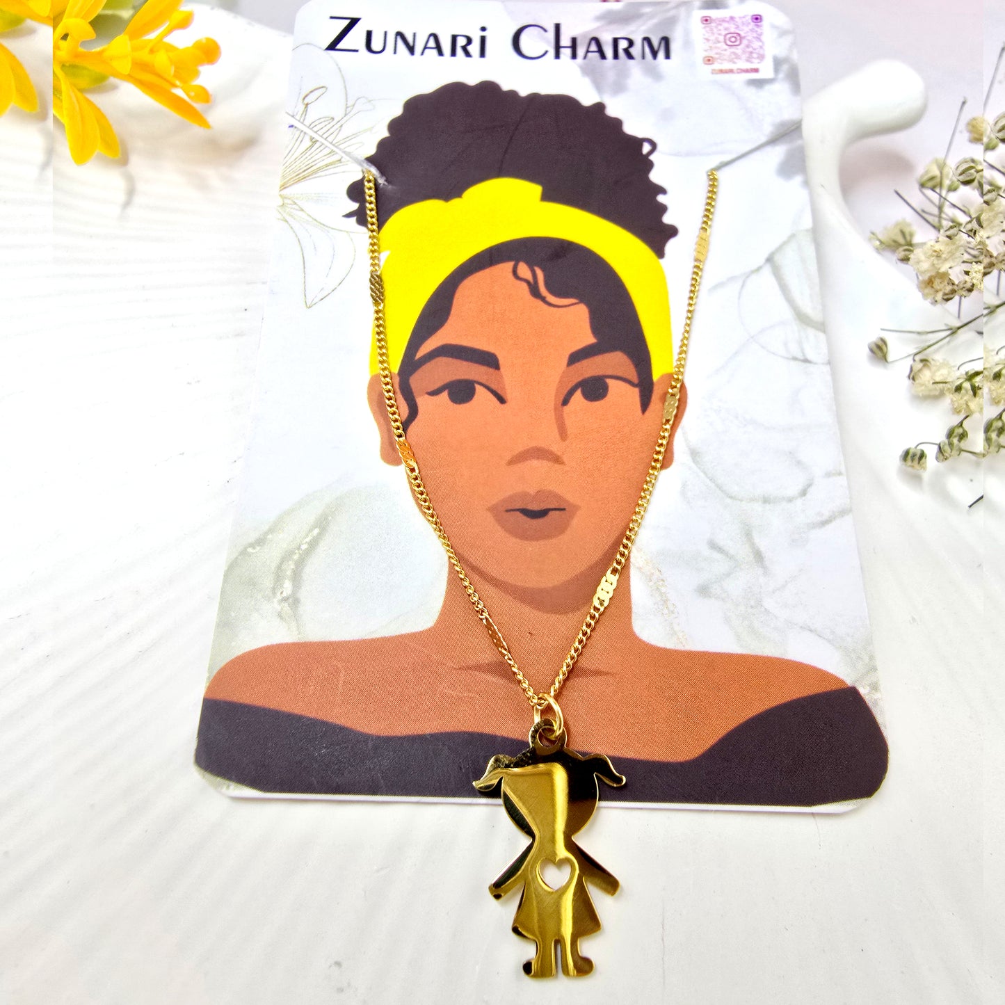 Zunari Charm gold little girl pendant displayed on a brand jewelry card.