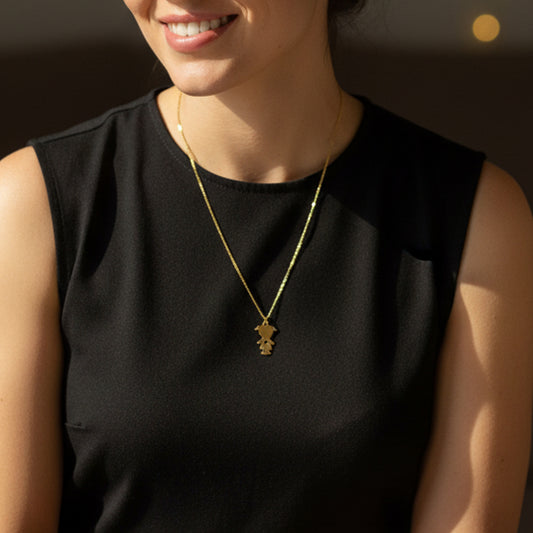 Model wearing the gold little girl necklace against a black sleeveless top, showcasing the length and scale.