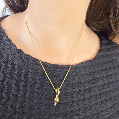 Model wearing Little Girl 3D Necklace – gold pendant chain styled with black top