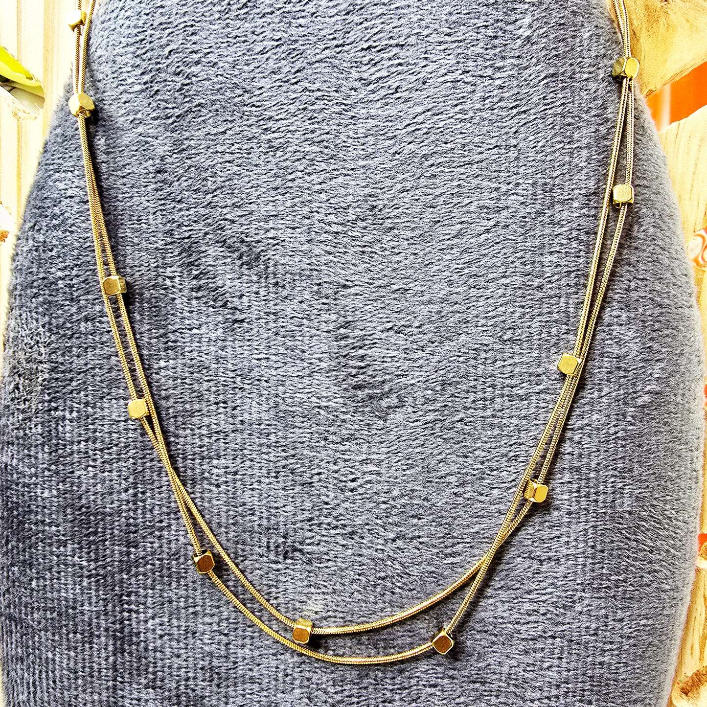 Necklace on grey display stand – close-up of geometric cube bead details