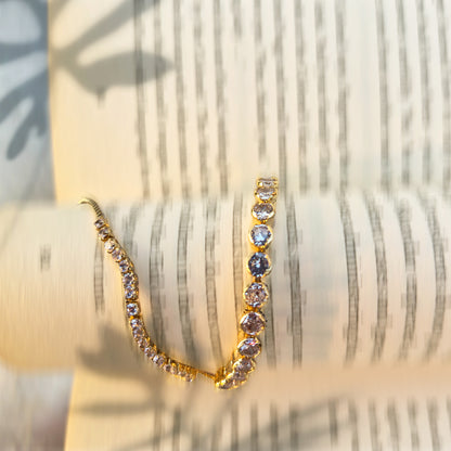 Close-up of sparkling cubic zirconia crystals on gold double-strand bracelet.