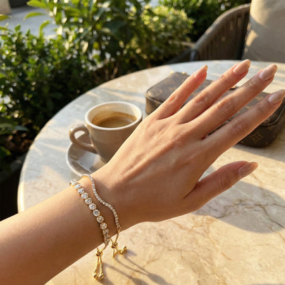 Woman's hand wearing double-layered gold crystal tennis bracelet with adjustable slider.