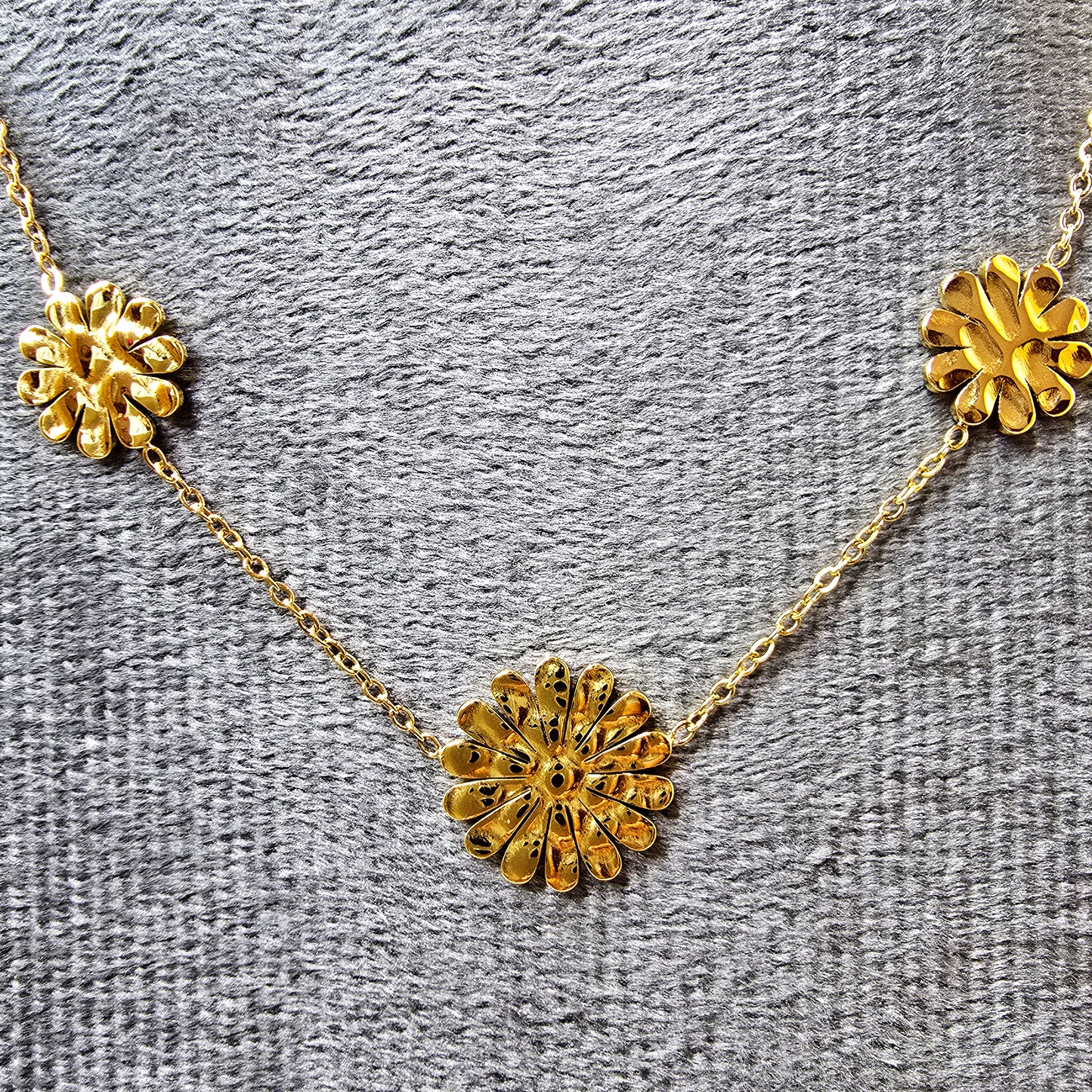 Close-up of the textured gold marigold flower charms on a grey fabric background.
