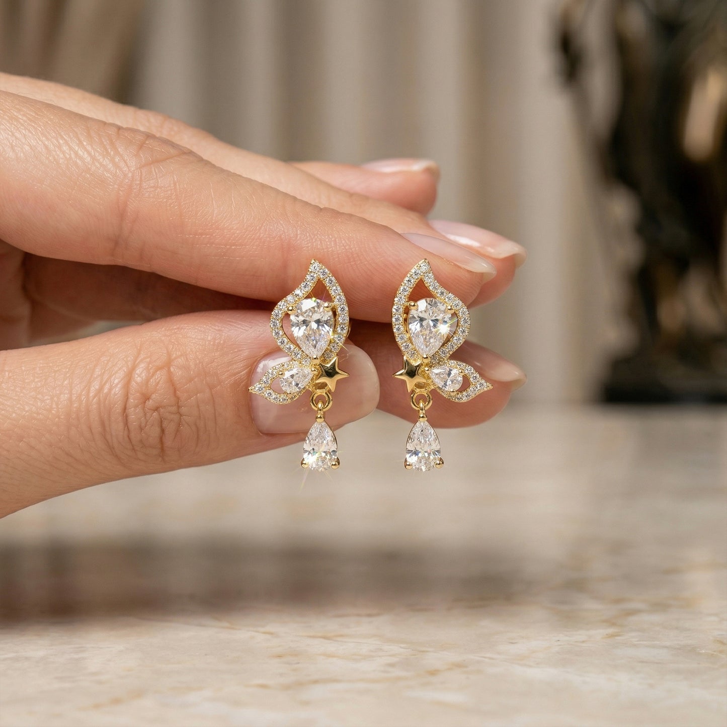 gold statement earrings hand holding mariposa design