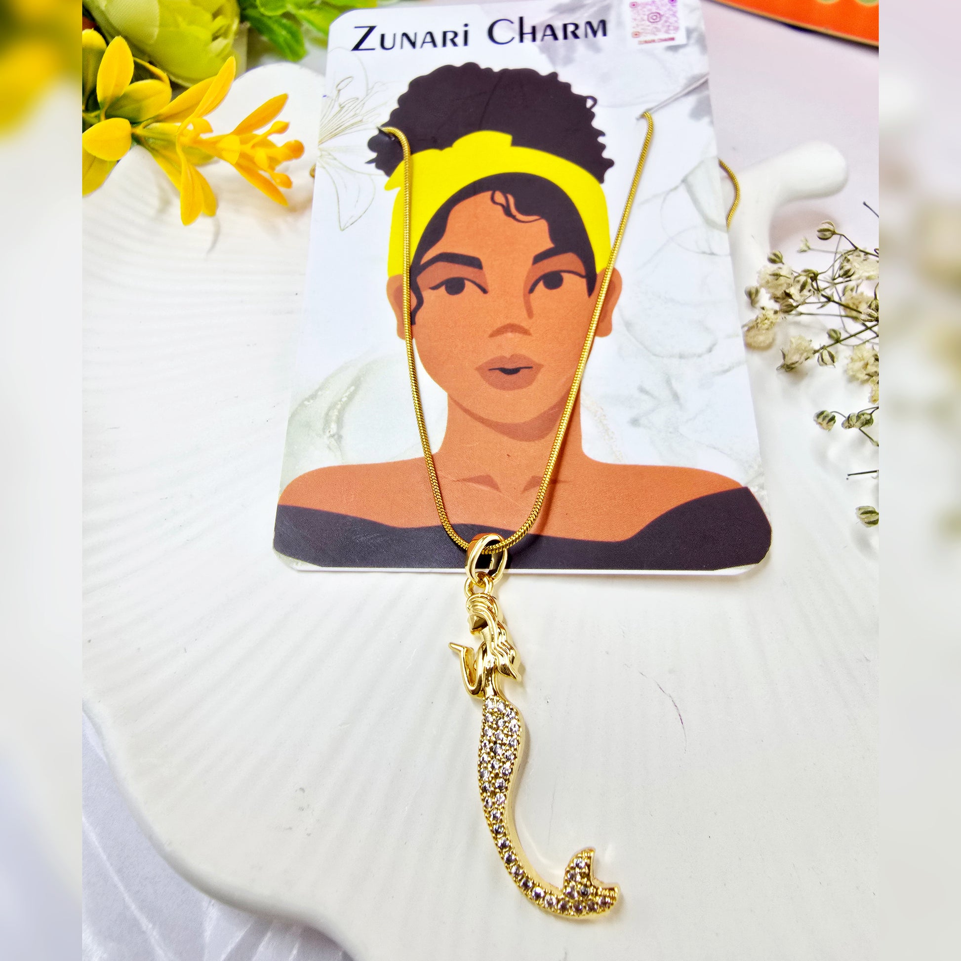Gold mermaid pendant necklace displayed on  Zunari Charm jewelry card with a diverse model illustration.