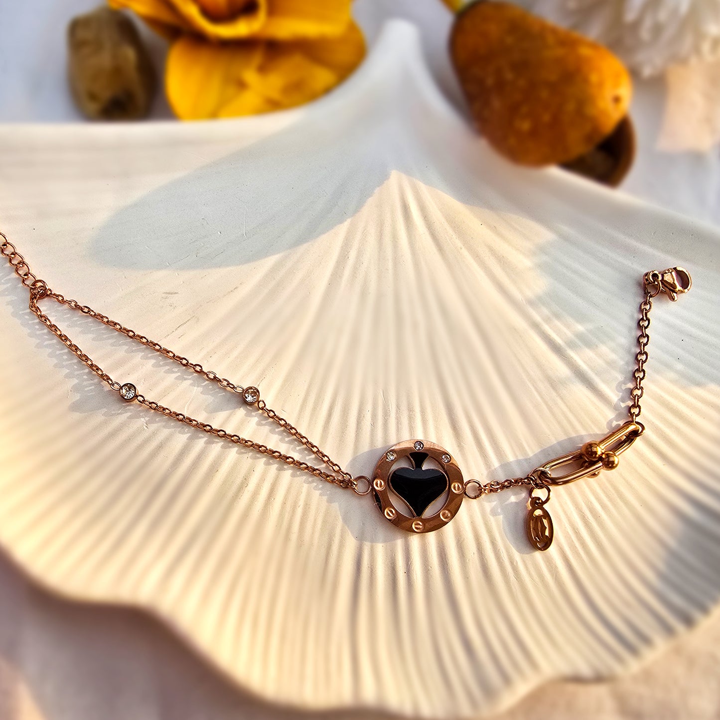 Flat lay of the gold spade bracelet displayed on a decorative white shell tray.