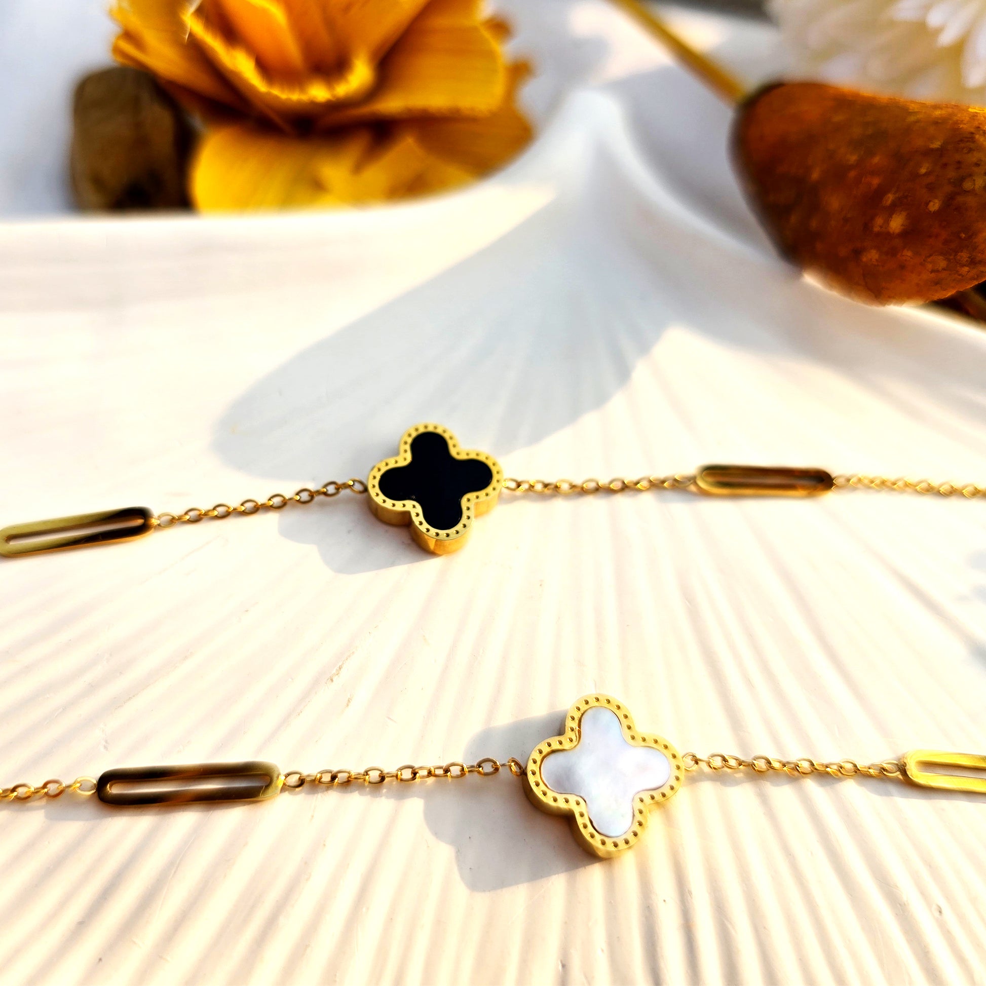 Flat lay comparison of the Midnight (Black) and Marble (White) gold clover bracelets.