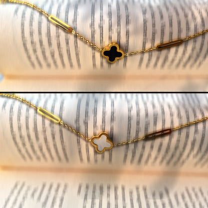 Close-up detail of the elongated paperclip links and the black vs. white clover charms.
