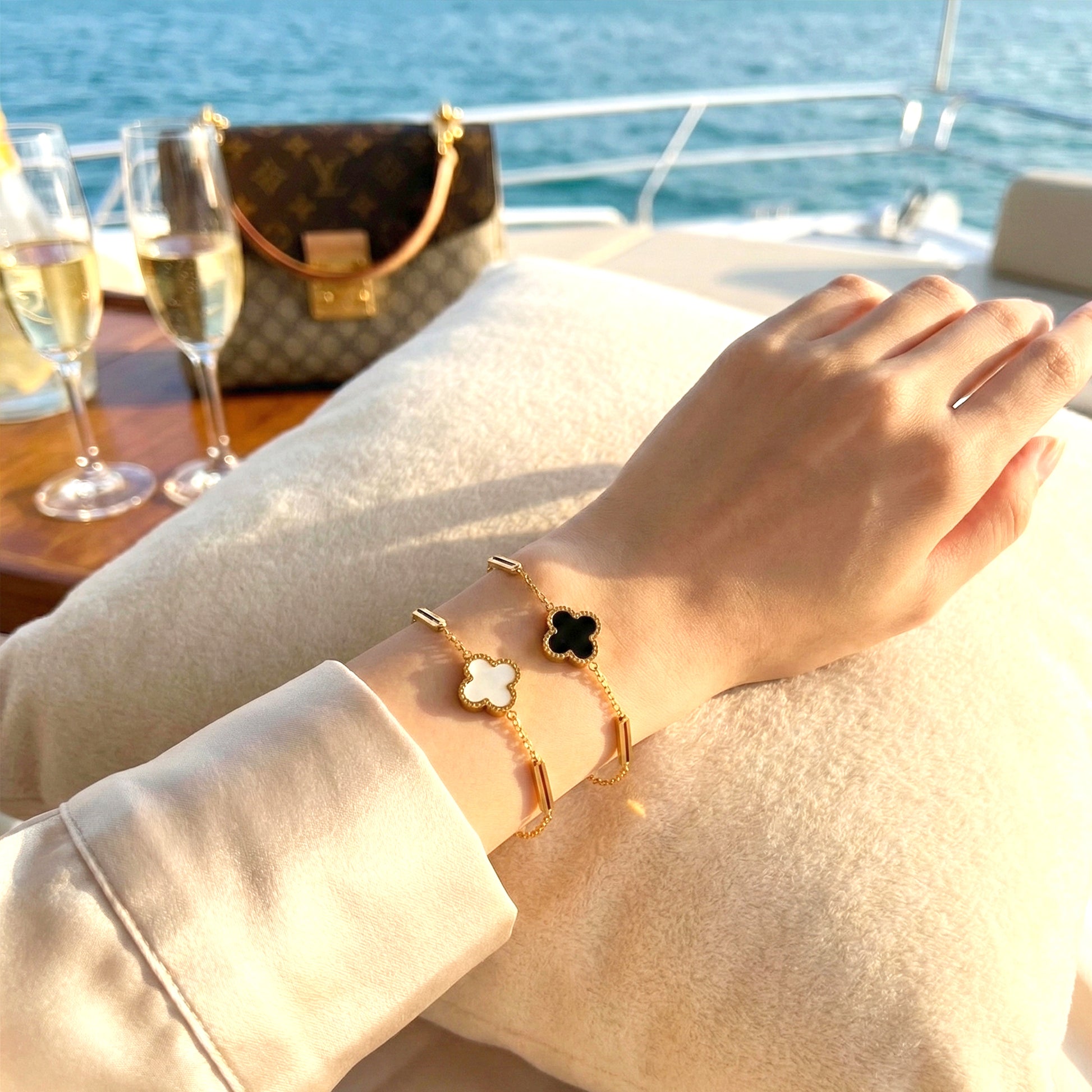 Woman on a yacht wearing both black and white Midnight & Marble clover bracelets stacked.