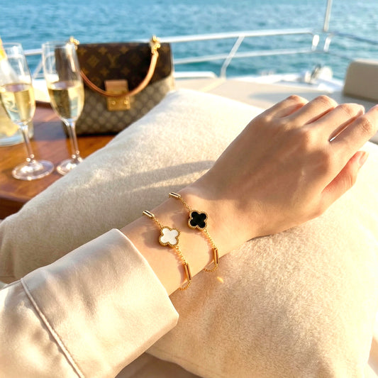 Woman on a yacht wearing both black and white Midnight & Marble clover bracelets stacked.