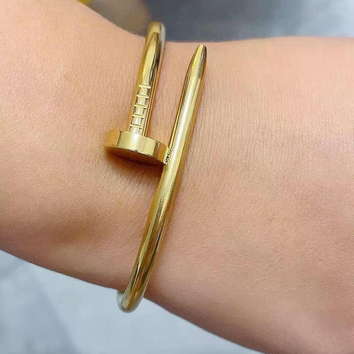 Gold nail bracelet worn on wrist, showcasing its edgy design