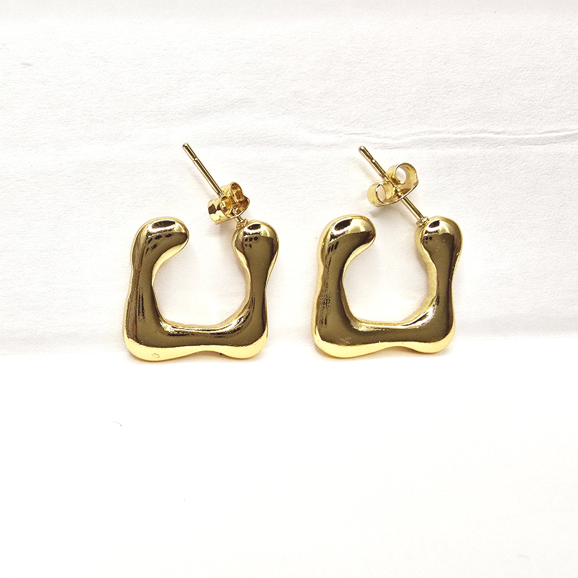 Modern Melt Earrings – Gold abstract hoops on white background