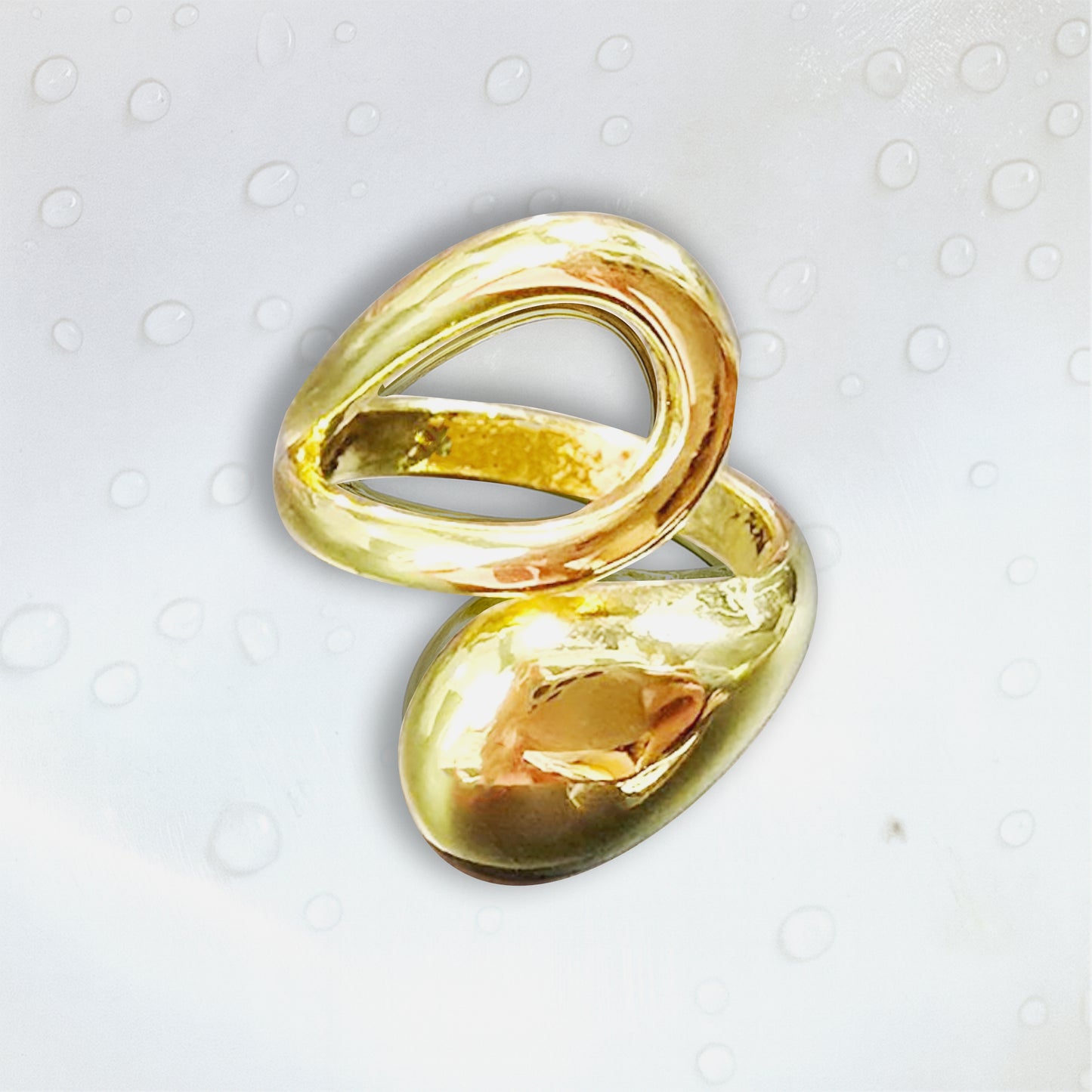 Gold molten drop ring on white background with water droplets, minimalist jewelry product photo.
