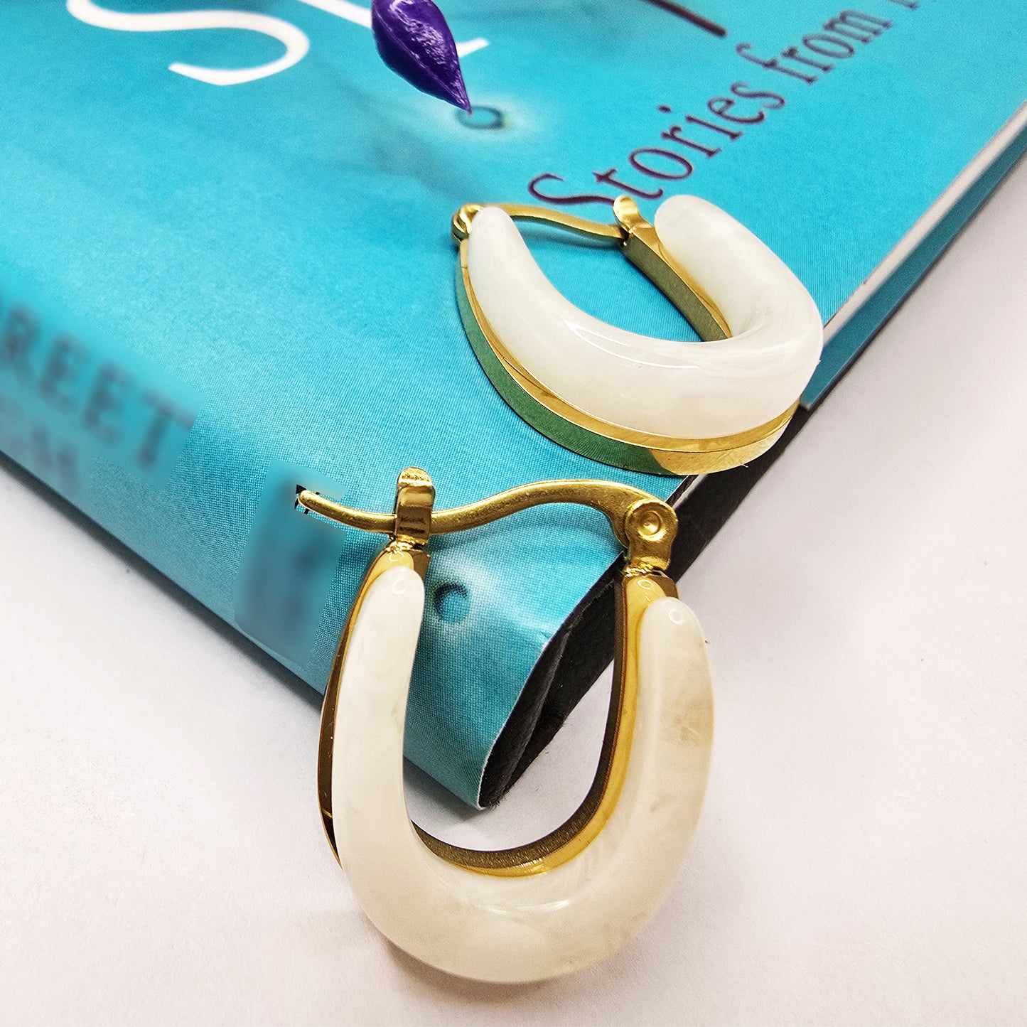 Moonlit Loop Earrings – chic ivory hoop earrings styled on a blue book
