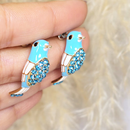 Close-up of blue crystal bird earrings held in hand