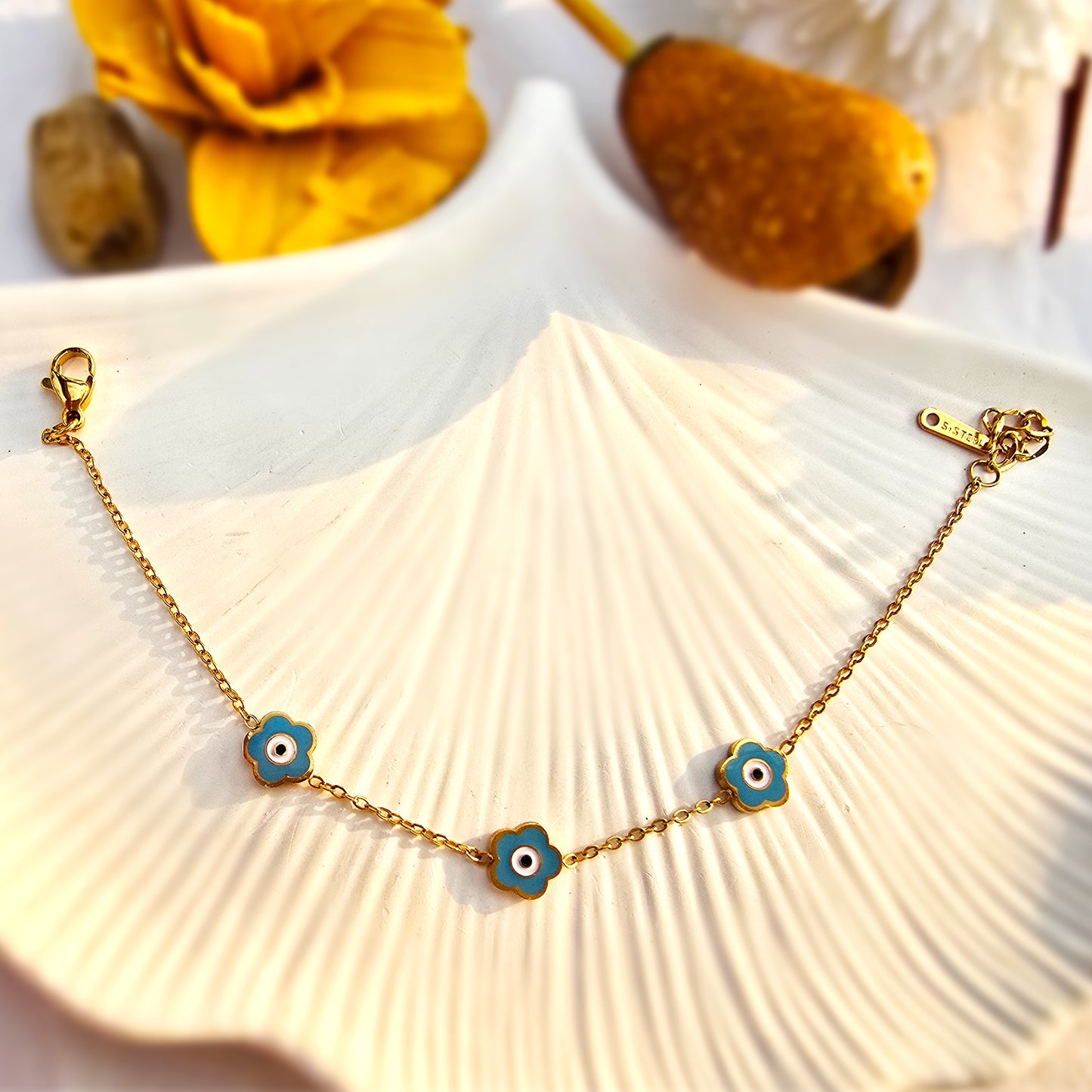 Flat lay of the full teal bracelet on a white shell, showcasing the gold fancy link chain.