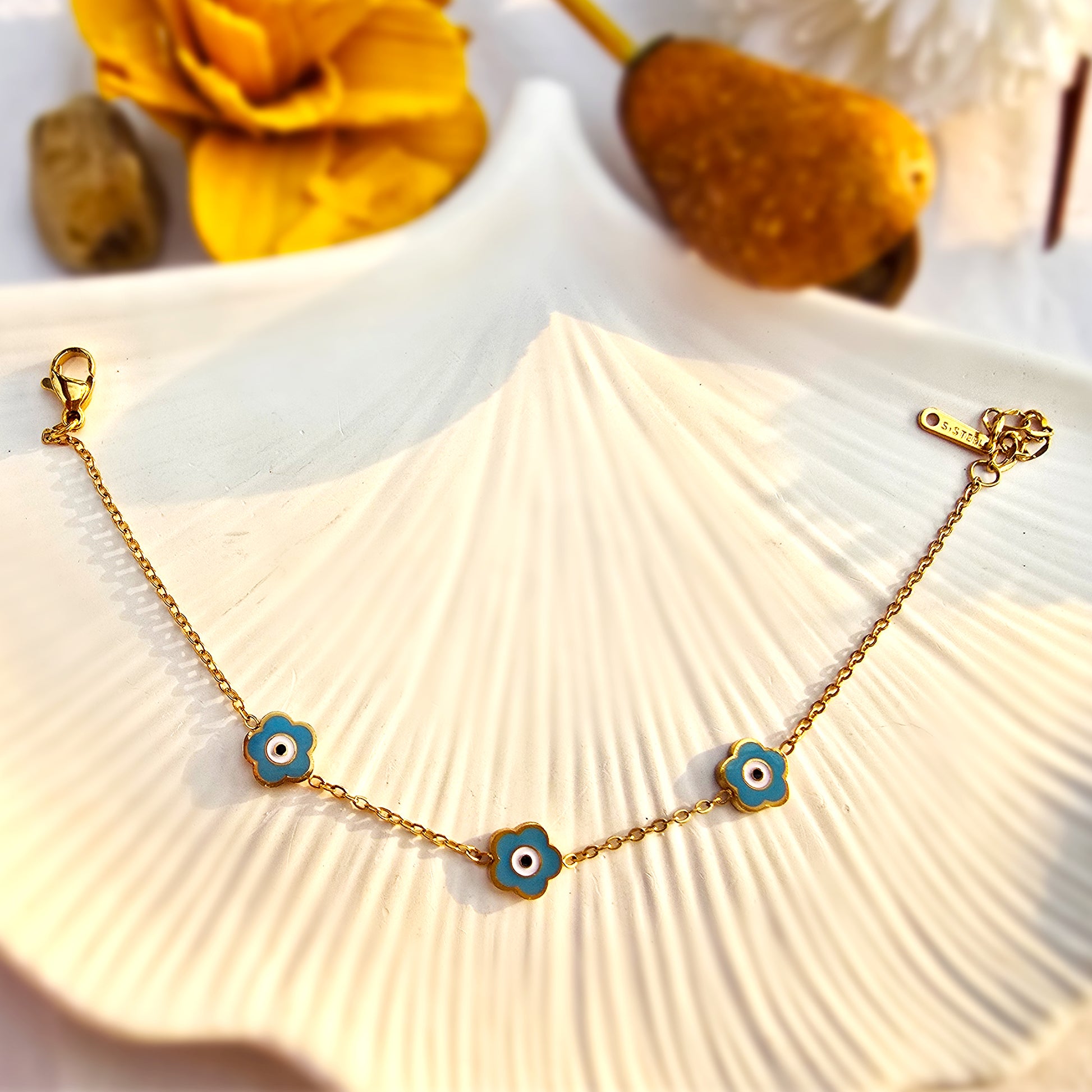 Flat lay of the full teal bracelet on a white shell, showcasing the gold fancy link chain.