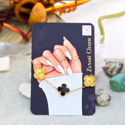 Noir Eclipse black and gold clover bracelet displayed on Zunari Charm branded packaging card.