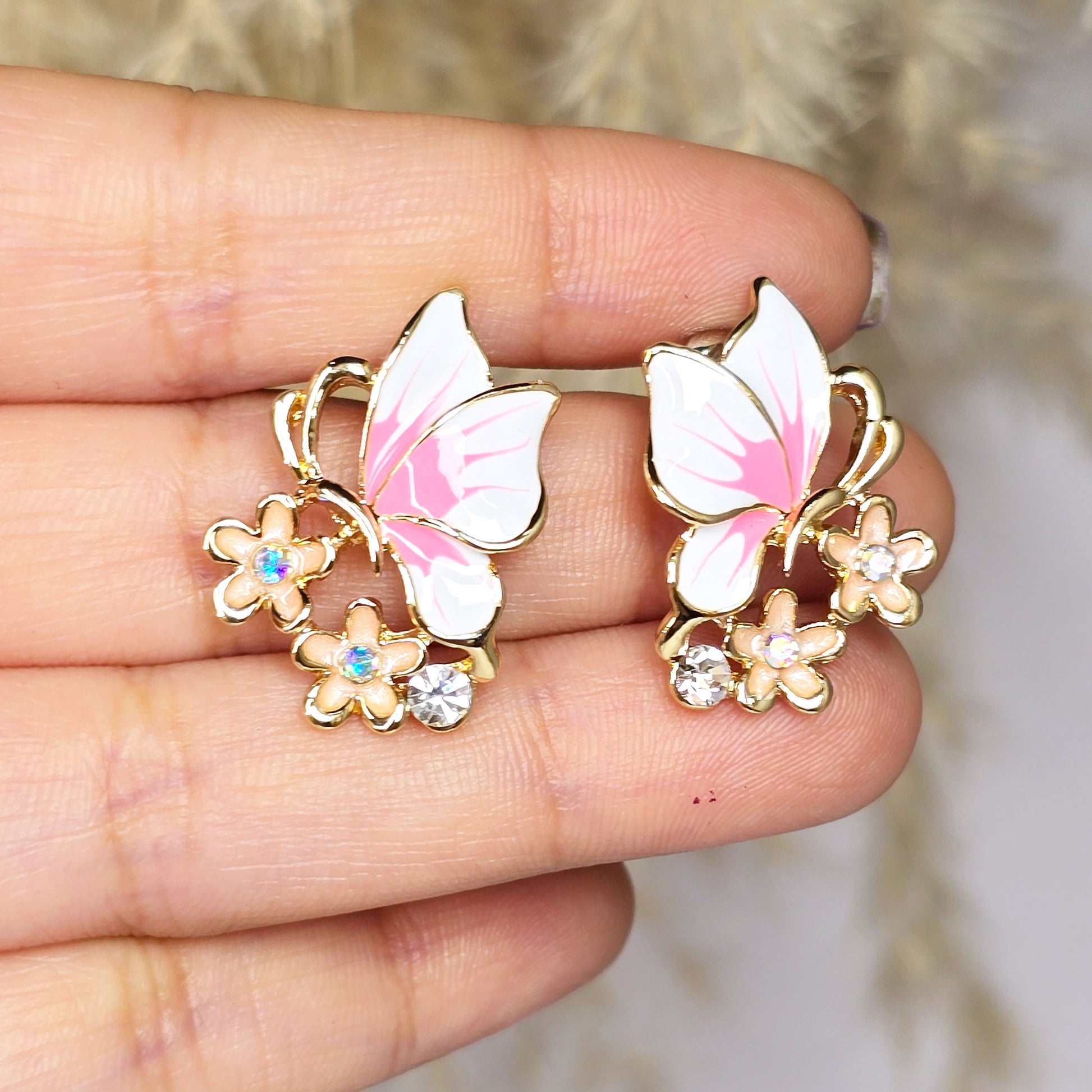 Close-up of pink butterfly earrings held in hand