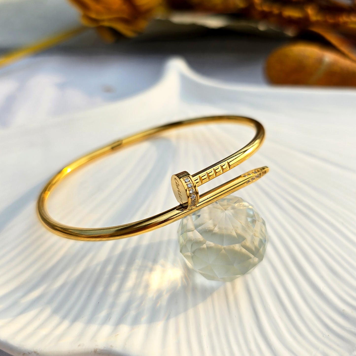 Flat lay of gold crystal nail cuff bracelet on a white shell tray.