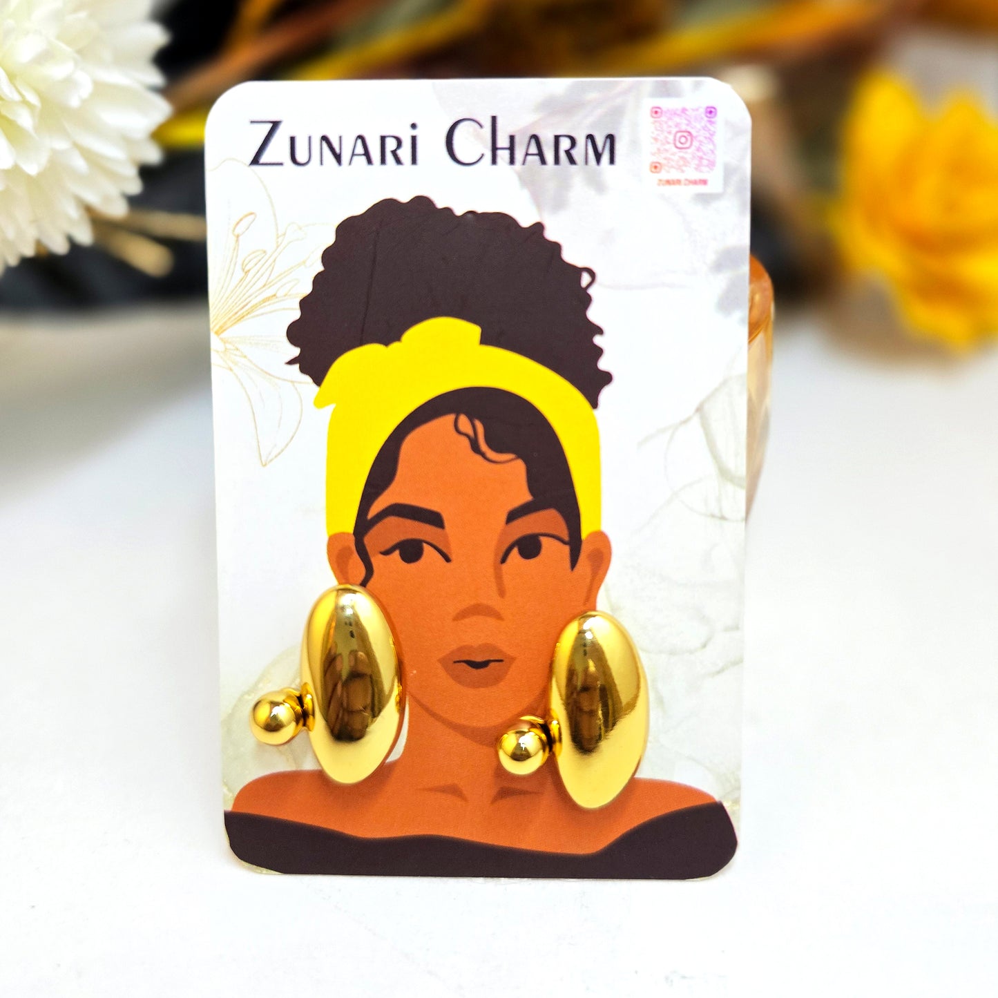 Pebble sculptural earrings displayed on a Zunari Charm branded card featuring an illustrated woman in a yellow turban.