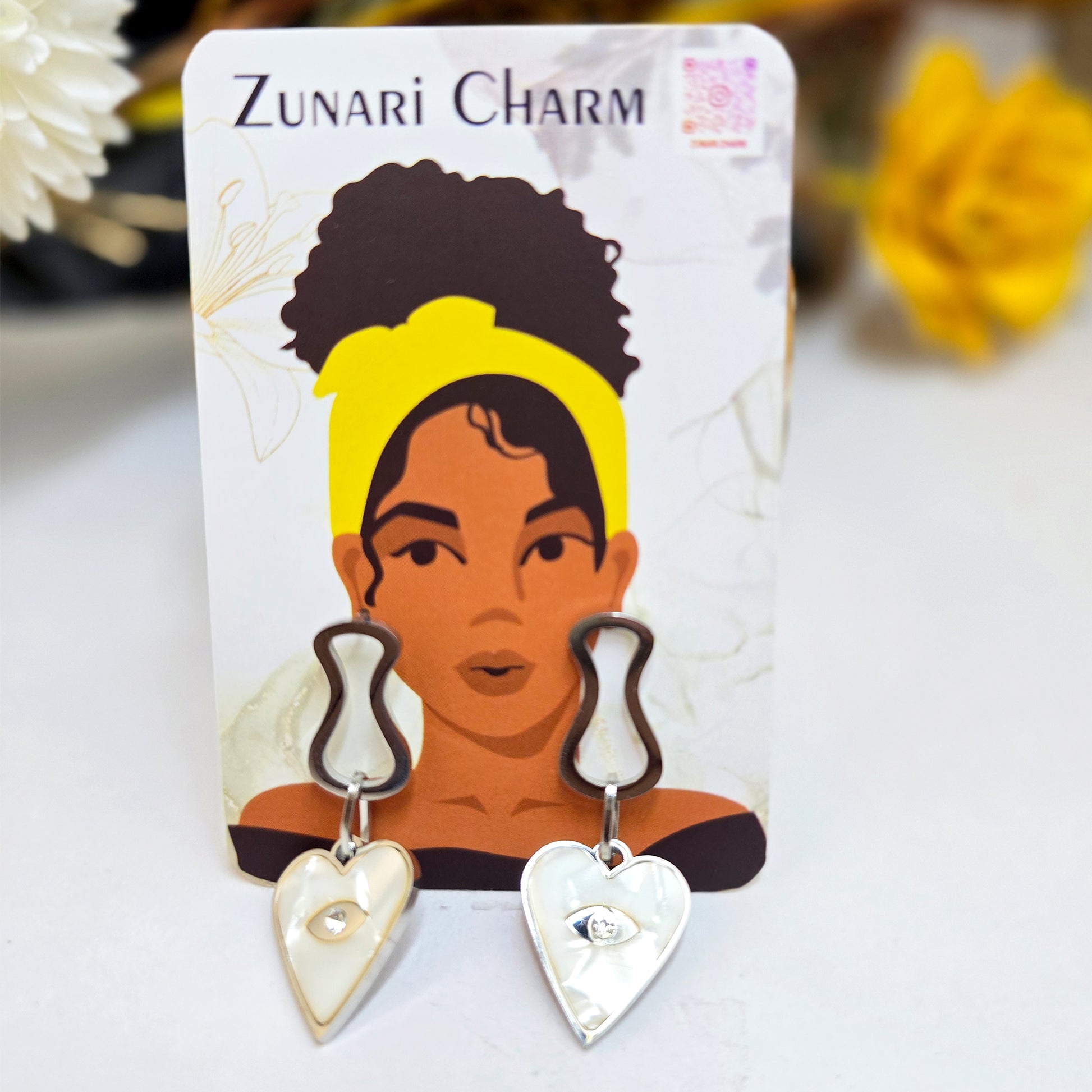 Prism Eye heart earrings displayed on a Zunari Charm branded card with the signature yellow-turban woman illustration.