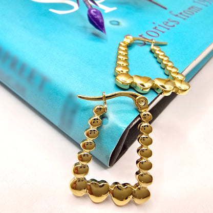Rectangle Heart Hoop Earrings – chic gold hoops placed on a blue book