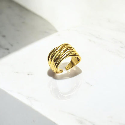 Ripple Band Ring on marble background, highlighting its gold shine and adjustable open band.