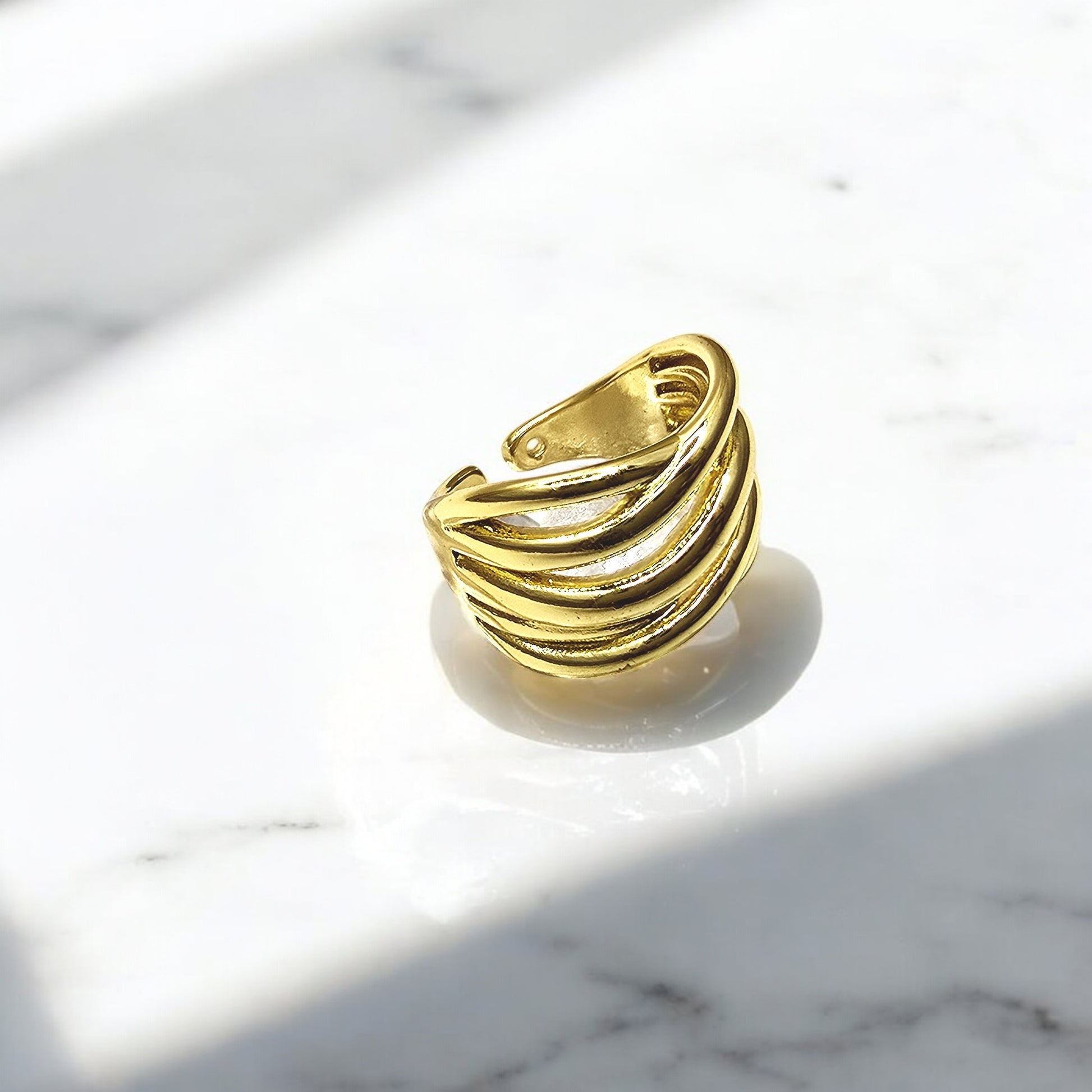Gold Ripple Band Ring in angled light, emphasizing layered ripples and glossy finish.