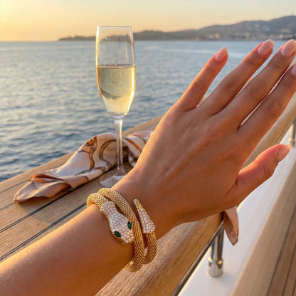 Woman wearing gold serpent mesh cuff on yacht background, styled with luxury resort wear.