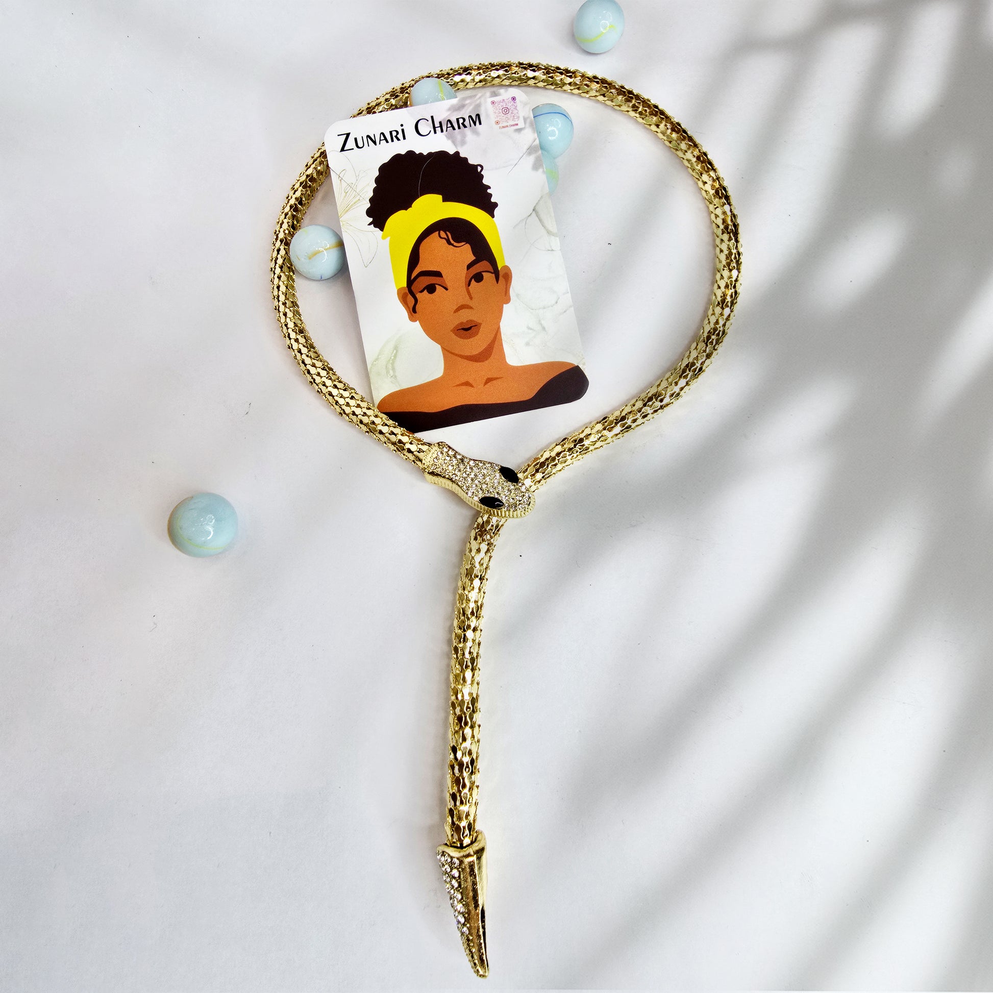 Packaging flatlay – Serpent Embrace Necklace with Zunari Charm brand card