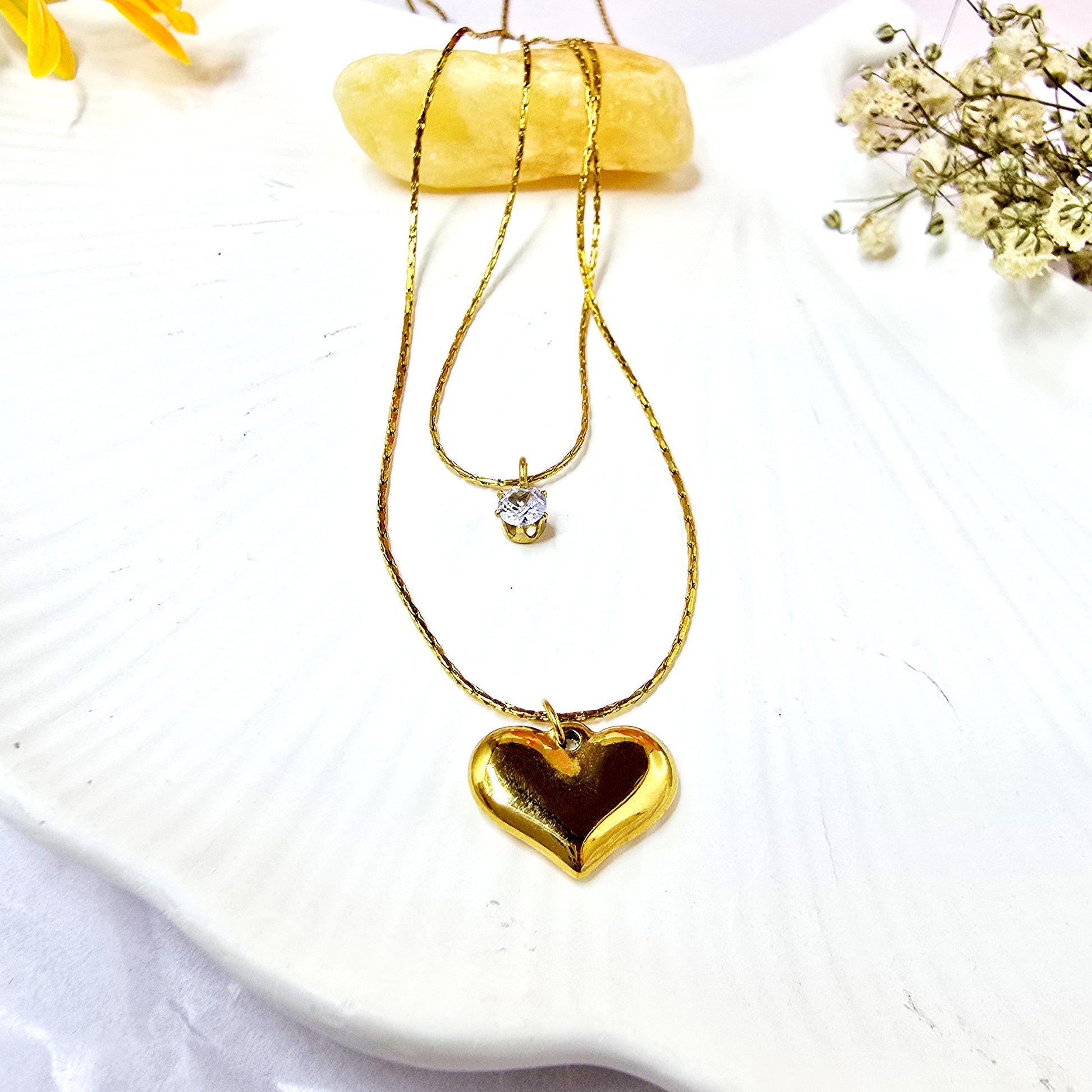 Shine in Love Pendant Chain on shell background featuring two-layer gold necklace with crystal and heart pendants.