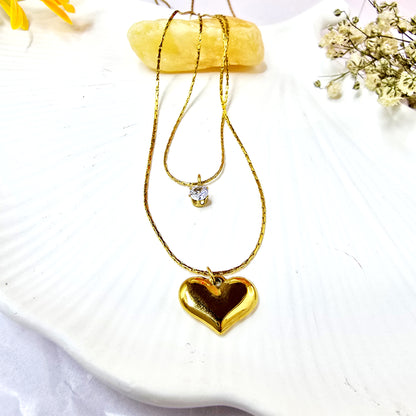 Shine in Love Pendant Chain on shell background featuring two-layer gold necklace with crystal and heart pendants.