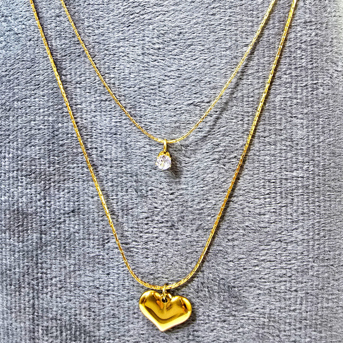 Close-up of Shine in Love Pendant Chain on grey velvet surface showing sparkle and gold detailing.