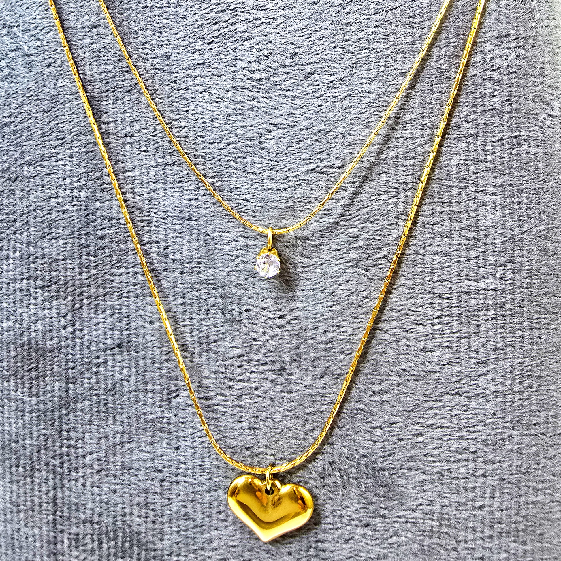 Close-up of Shine in Love Pendant Chain on grey velvet surface showing sparkle and gold detailing.