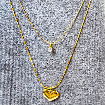 Close-up of Shine in Love Pendant Chain on grey velvet surface showing sparkle and gold detailing.