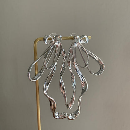 Earrings hung on a gold stand showcasing curved silhouette and polished finish